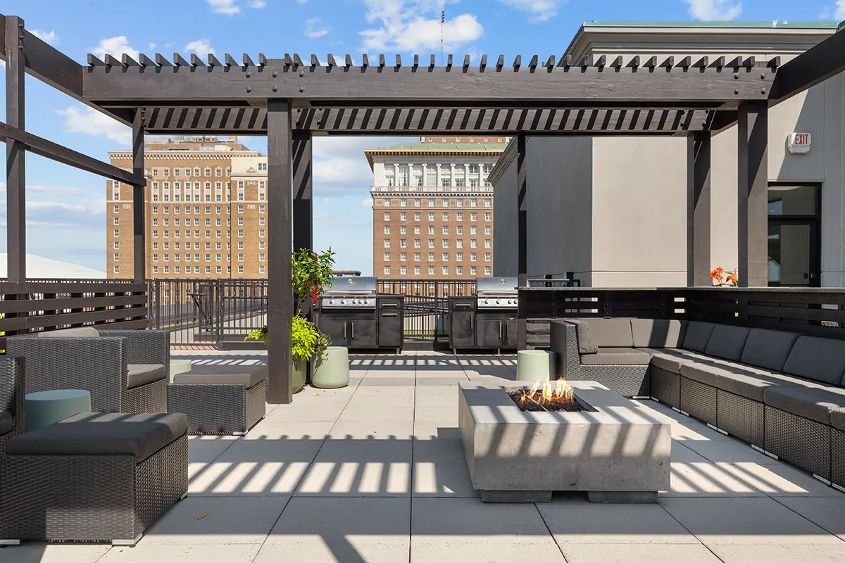 Rooftop terrace at Six Cord Apartments with pergola, lounge seating, fire pit, grilling station, and downtown St. Louis cityscape views