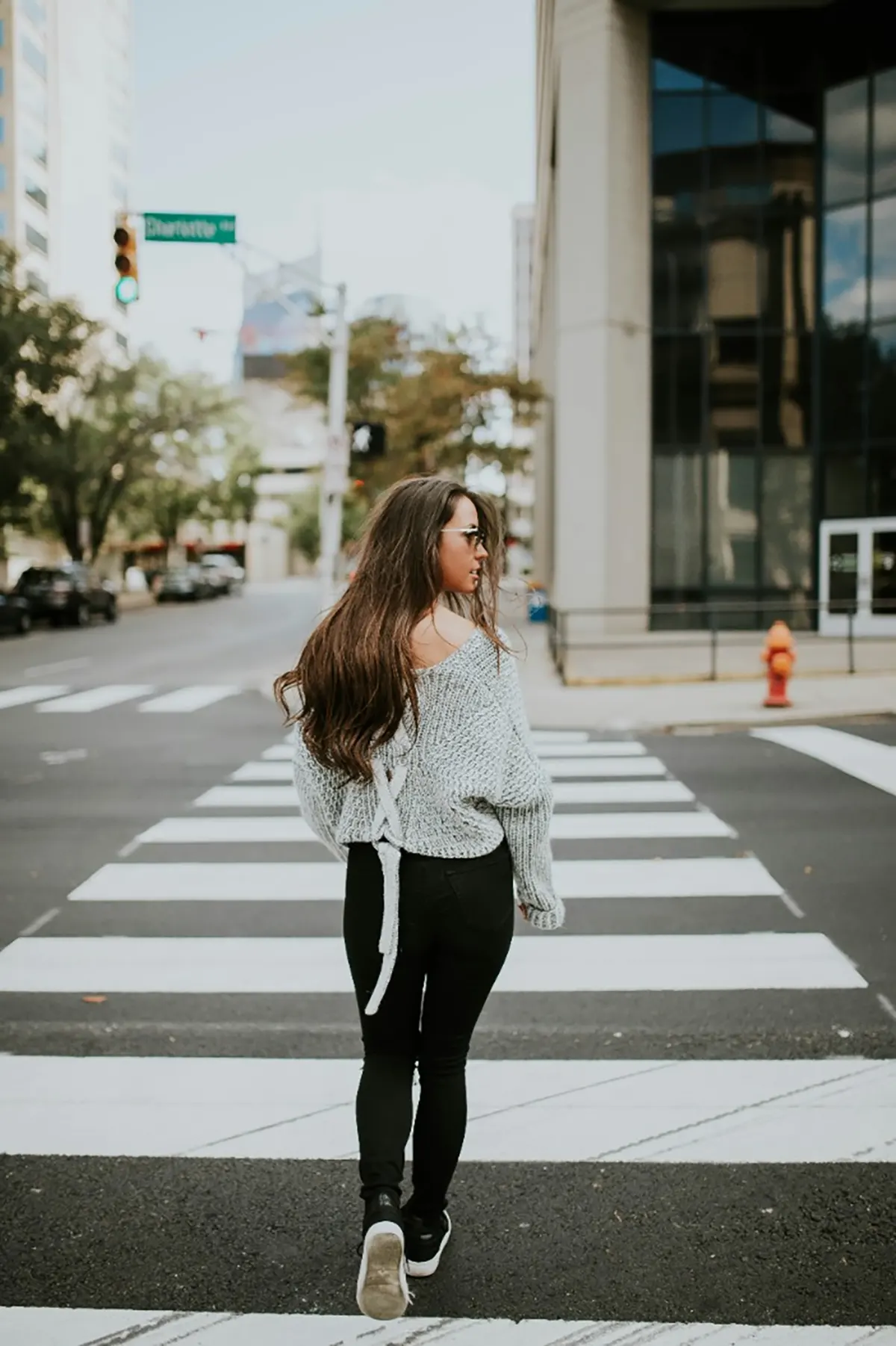 Brown haired woman walking across a crosswalk in Downtown St. Louis, MO