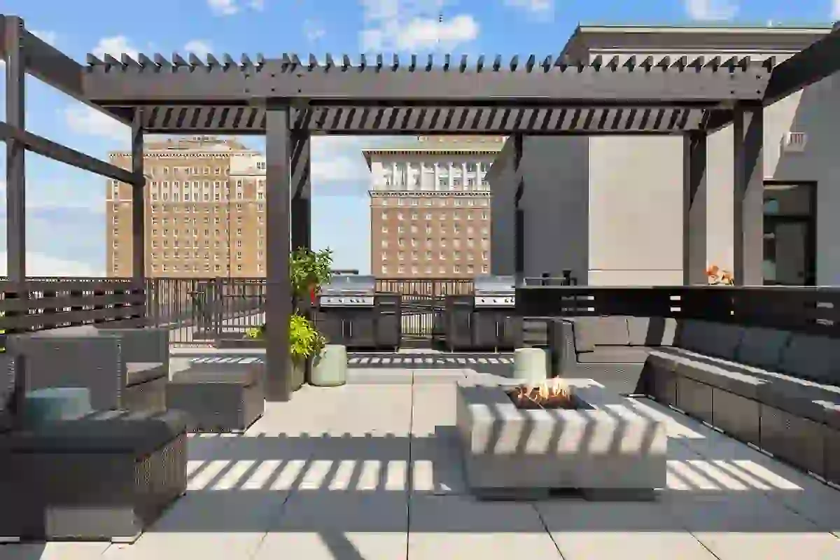 Rooftop terrace at Six Cord Apartments with pergola, lounge seating, fire pit, grilling station, and downtown St. Louis cityscape views