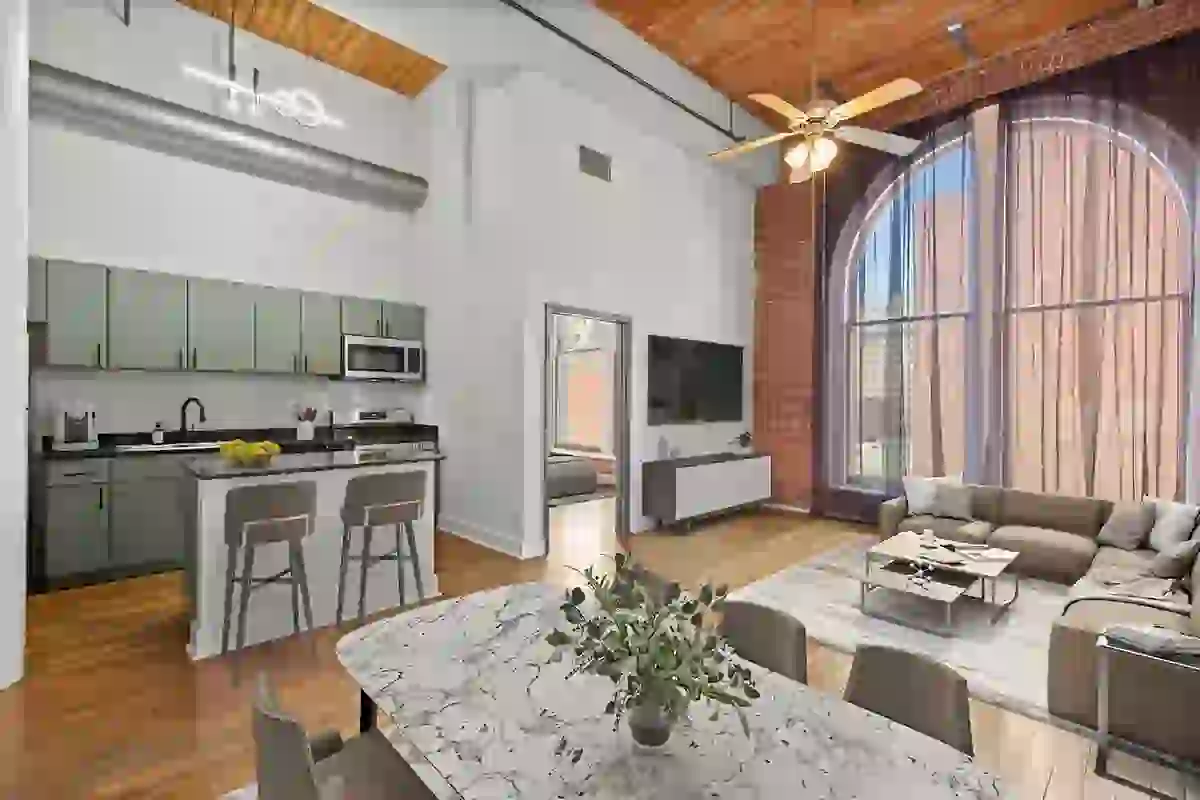 Modern kitchen finishes with nuetral cabinetry, black quartz countertops, stainless-steel appliances, hardwood floors, and exposed red brick
