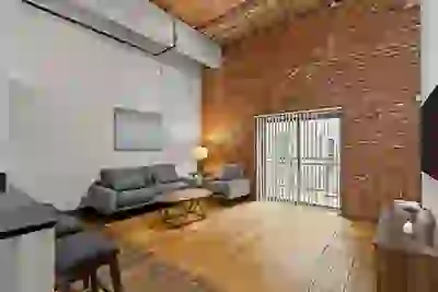 Six Cord Apartments living room with high ceilings, exposed brick, and slatted wood ceiling