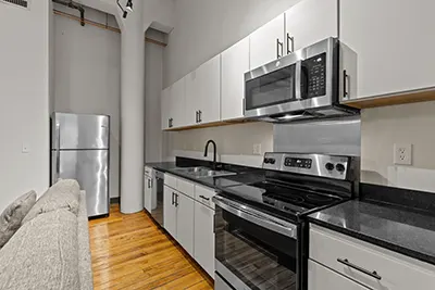 Stainless steel appliances with light cabinetry and dark quartz countertops in kitchen at Six Cord Apartments