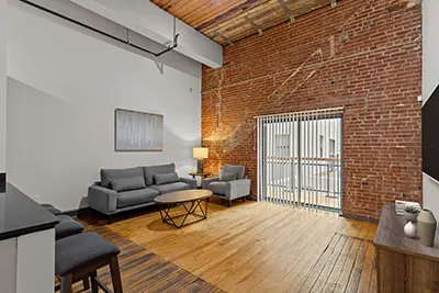 Six Cord Apartments living room with high ceilings, exposed brick, and slatted wood ceiling