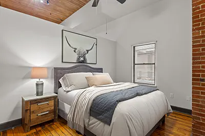 Bedroom at Six Cord Apartments with hardwood floors beneath a large bed