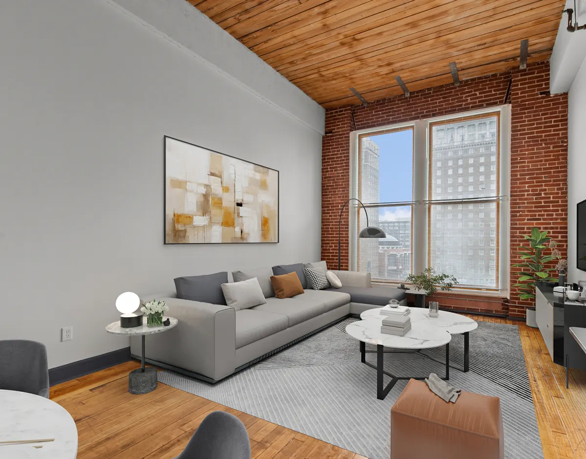 Loft-style living room with exposed brick, hardwood floors, and large windows with downtown city views